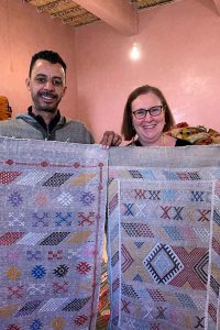 Tourist and seller showing rugs for sale in shop in Morocco