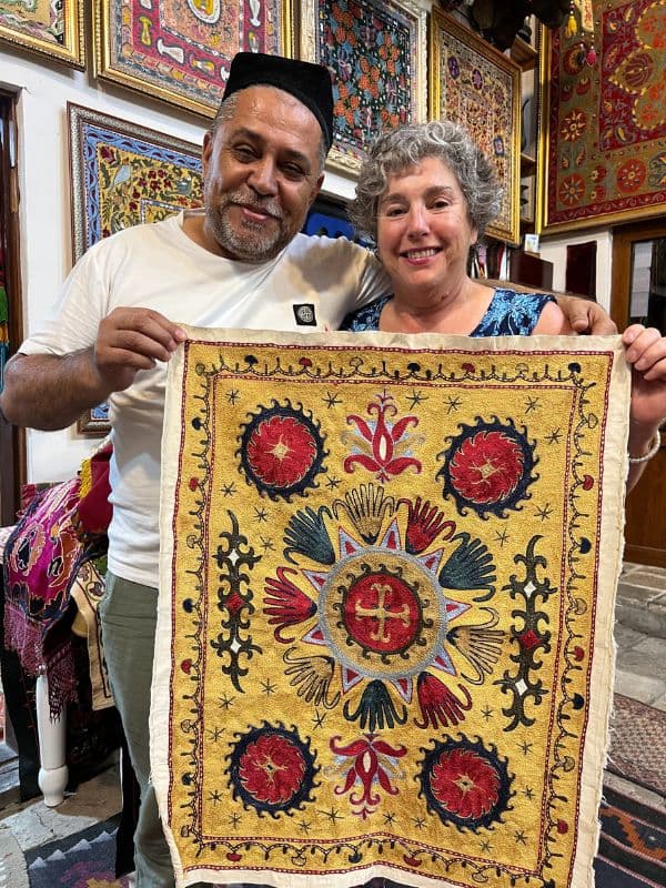 Uzbek man with tourist holding yellow suzani embroidery