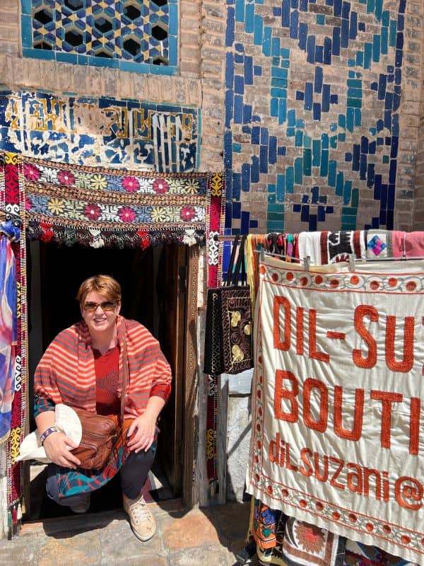 lady crouching in small doorway surrounded by textiles